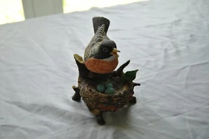 A Bird Sitting on a Branch with a Bird Nest that Has Three Blue eggs in it. - Picture 1 of 12