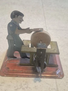 AFILADOR DE CUCHILLOS DE CUERDA DE JUGUETE DE COLECCIÓN LITOGRAFÍA DE HOJALATA HOMBRE PIEDRA DE AFILAR CUERDA DE METAL - Imagen 1 de 7