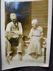 OLD COUPLE SITTING ON FRONT STEPS READING A NEWSPAPER 1910's PHOTO