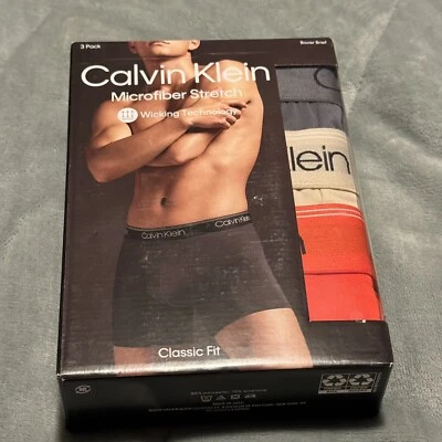 Paquete de 3 calzoncillos boxer Calvin Klein micro elásticos para hombre talla pequeña gris, crema, naranja Foto 1 de 3