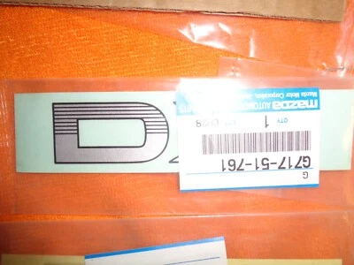 NOS 1990 1991 1992 MAZDA 626 "DX" CALCOMANÍA/EMBLEMA GUARDABARROS DELANTERO G717-51-761 NUEVO OEM Foto 1 de 4