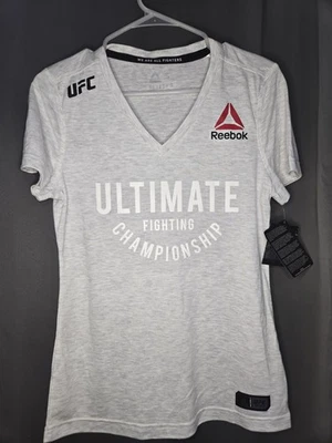 NUEVO CON ETIQUETAS Camiseta Reebok UFC Para Mujer Manga Corta Cuello en V Gris Pequeña Foto 1 de 4