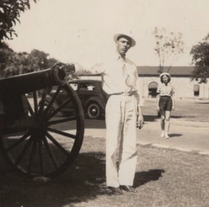 1938 Man Next Cannon Hat White Attire Woman Walking Background Portrait - Picture 1 of 3