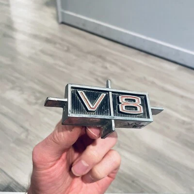 Oldsmobile F-85 Cutlass 1964-1966 guardabarros moldura emblema V/8 insignia V8 GM # 589421 Foto 1 de 4