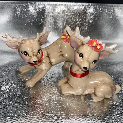 Pair of vintage Christmas reindeer babies, one lying on silver with red antlers, one standing with floral headband.