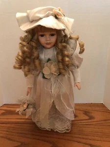 Muñeca de porcelana de 16" con vestido, sombrero y bolso satinado gris claro/blanco roto  - Imagen 1 de 11