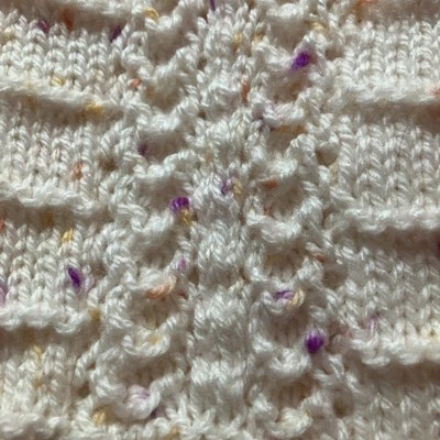 Hermosa manta de bebé tejida a mano. Melocotón pálido con pequeñas manchas de amarillo/lila Foto 1 de 4