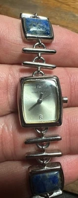 Reloj para damas NINE WEST esfera plateada con detalles de piedra lapislázuli azul - necesita murciélago Foto 1 de 4