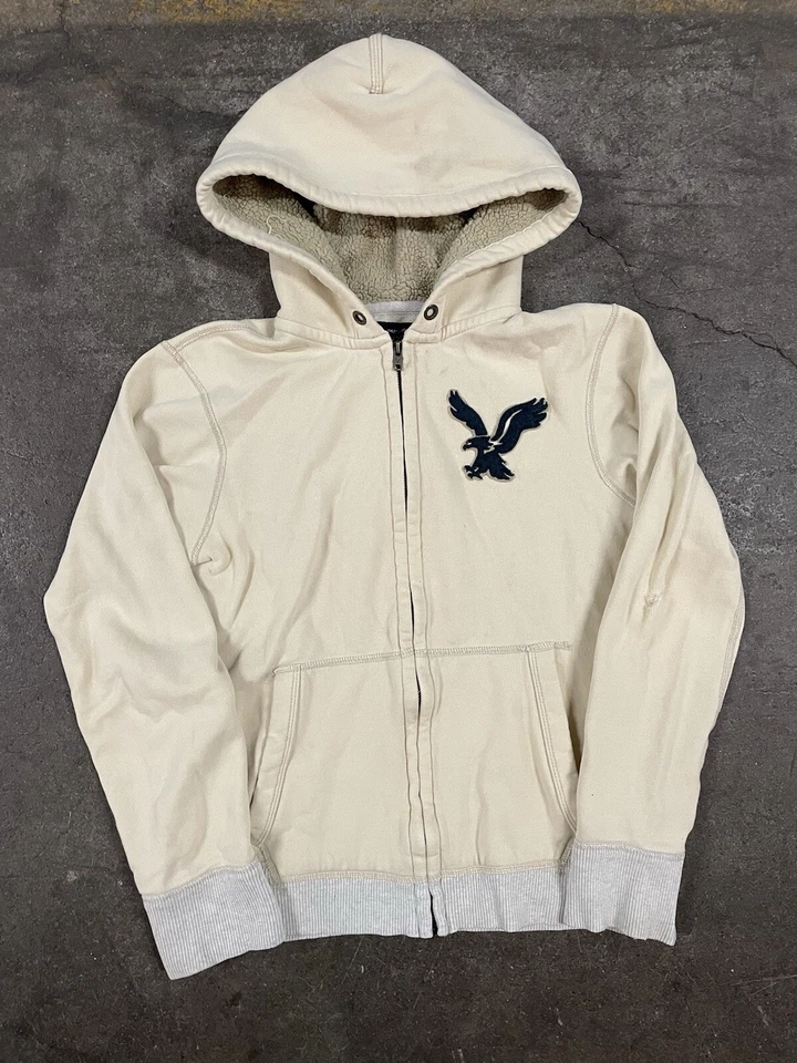 Sudadera con Capucha American Eagle Marfil Para Mujer Pequeña Cremallera Sherpa Forrada Clásica Grande Logo Foto 1 de 4