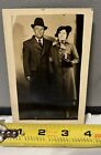 Vintage RPPC of Older Man And Woman With Trench Coats, Hats And Cigarette