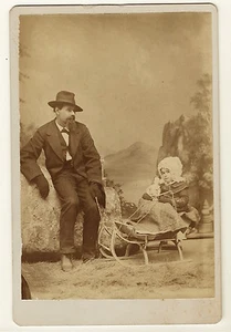 SLOUCHING DAD PULLS YOUNG DAUGHTER ON A SLED IN BELLEVUE, OHIO (CABINET CARD) - Picture 1 of 2
