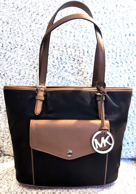 Bolso de Mano Michael Kors Jet Setter Nylon Negro con Borde de Cuero Marrón y Dije Foto 1 de 4