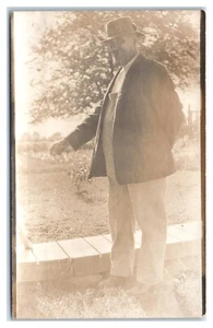 RPPC Caballero Mayor en Mono Chaqueta y Sombrero Alimentación Perro Postal - Imagen 1 de 2