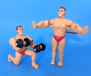 Zwei Aufziehspielzeug Kunststoff Bodybuilder 3" groß Bizeps Locken & Liegestütze Spaß Neuheit - Bild 1 von 5
