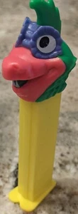 PEZ-a-Saurs Dinosaurier Süßigkeitenspender gelber Stiel rosa/grüner Kopf lila Augen - Bild 1 von 5