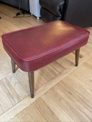 Taburete otomano vintage de vinilo rojo de mediados de siglo con patas cónicas de madera y metal Foto 1 de 4