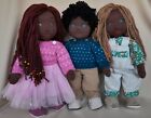 Three black Waldorf dolls with additional clothes and pajamas