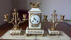 An early 20th C French gilt metal & marble clock with a pair of candlesticks