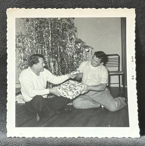 ZWEI MÄNNER TAUSCHEN WEIHNACHTSGESCHENKE IN DER NÄHE VON WEIHNACHTSBAUM SCHNAPPSCHUSS FOTO-DENVER CO - Bild 1 von 3