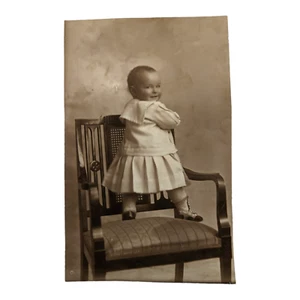 Found Photo Baby Stands On Chair Mischievous Smile - Picture 1 of 4