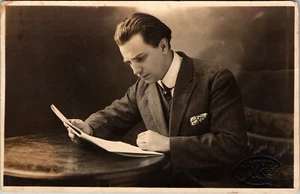 HANDSOME AND WELL DRESSED YOUNG MAN INTENTLY READING A MAGAZINE - Picture 1 of 3