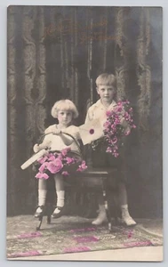 Postcard RPPC Birthday Girl & Boy Holding Flowers Hand Colored Cute c1910 - Imagen 1 de 2