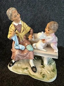 Estatuilla vintage NORLEANS abuela tejiendo y bebé niño con perro en banco - Imagen 1 de 23