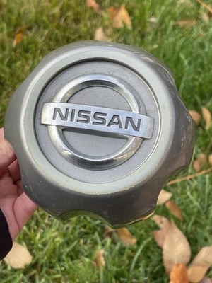 Tapa central de rueda Nissan Xterra Frontier 1999-2015 OEM gris grafito cromo logotipo Foto 1 de 4