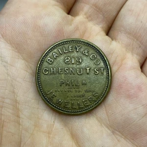 ENCASED POSTAGE STAMP-ONE CENT TOKEN BAILEY£CO.PHILADELPHIA JEWELLERS USA - RARE - Picture 1 of 4