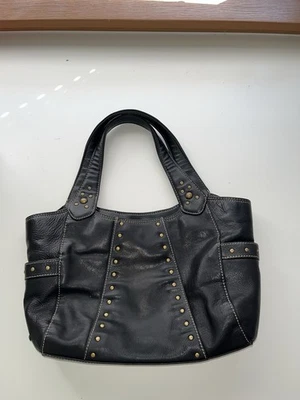 BOLSO DE MANO KENNETH COLE REACTION CUERO NEGRO CON TACHUELAS METÁLICAS Foto 1 de 4