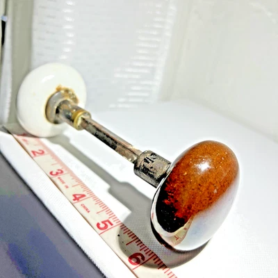 Manijas de perilla de puerta vintage de vidrio y metal una marrón y otra blanca con barra de metal Foto 1 de 4