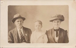 RPPC Studio Pose Grandparents w/ Child Wearing Religious Gown & Cap c. 1910 - Picture 1 of 2
