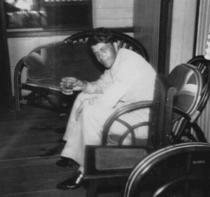Silla de porche de hombre guapo de la década de 1940 con bebida ligeramente desenfoque - Imagen 1 de 3