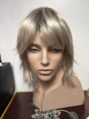 Peluca rubia platino con raíces sintéticas con flequillo. Estetica Jones en rubia iluminada por el sol Foto 1 de 4