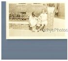 FOUND B&W PHOTO H_5616 TWO LITTLE GIRLS SITTING ON BRICK WALL WITH DOLLS