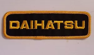 VINTAGE DAIHATSU EMBROIDERED PATCH WOVEN CLOTH BADGE SEW-ON MOTOR RACING YELLOW - Picture 1 of 1