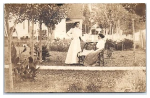 RPPC Zwei junge viktorianische Frauen in Weidenbank Vorgarten Postkarte - Bild 1 von 2