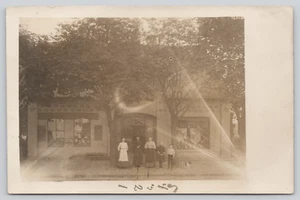 Postal RPPC Tres mujeres de pie en frente de tienda con niños y perro - Imagen 1 de 4