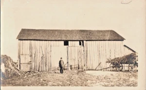Hombre de pie frente a su vagón de heno de granero postal antigua RPPC A103 - Imagen 1 de 2