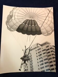 Vintage czarno-białe zdjęcie starzec parasailing spadochron wysoki budynek grymas