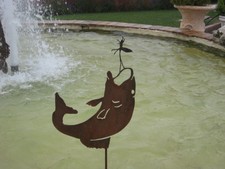 pesce che salta nel laghetto per catturare una libellula in acciaio Corten