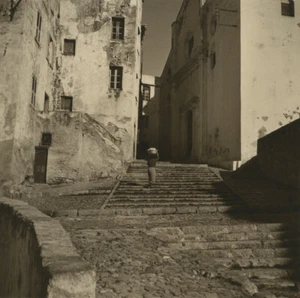 Corse. Femme chargée d'une bassine de linge montant un escalier à Calvi. - Foto 1 di 2