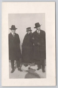 Postal RPPC Foto Real Dos Hombres con Sombreros Negros Abrigos Largos y Mujer Sombrero Elegante - Imagen 1 de 2