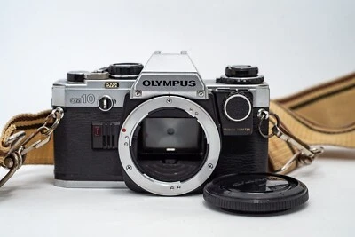 Reflex Argentique OLYMPUS OM-10 35mm Film + MANUAL ADAPTER/BOUCHON/SANGLE/PILES - Immagine 1 di 4