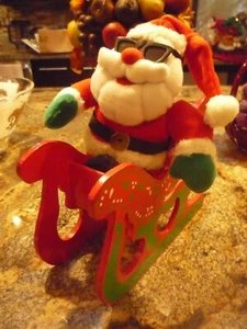 Prominenter im Besitz *COOLER TISCH-WEIHNACHTSMANN AUF HOLZSCHLITTEN MIT SCHWARZER SONNENBRILLE* 11x9,5 - Bild 1 von 3