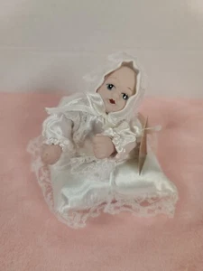 Bambola in porcellana miniatura occhi azzurri abito in pizzo bianco su cuscino bianco - Foto 1 di 7