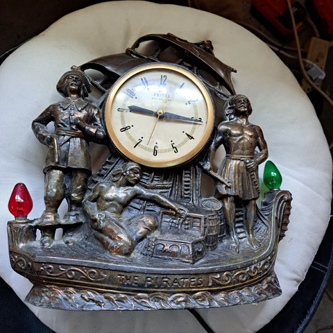 Antique UNITED "self starting brass/metal clock - 2 lights THE PIRATES Cover