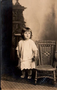 POSTAL RPPC NIÑA DE PIE JUNTO A UNA SILLA - Imagen 1 de 2