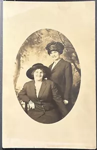 ECHTFOTO-POSTKARTE RPPC ~ ZWEI HÜBSCHE FRAUEN MIT HÜTEN ~ BÄUME STUDIO HINTERGRUND - Bild 1 von 2