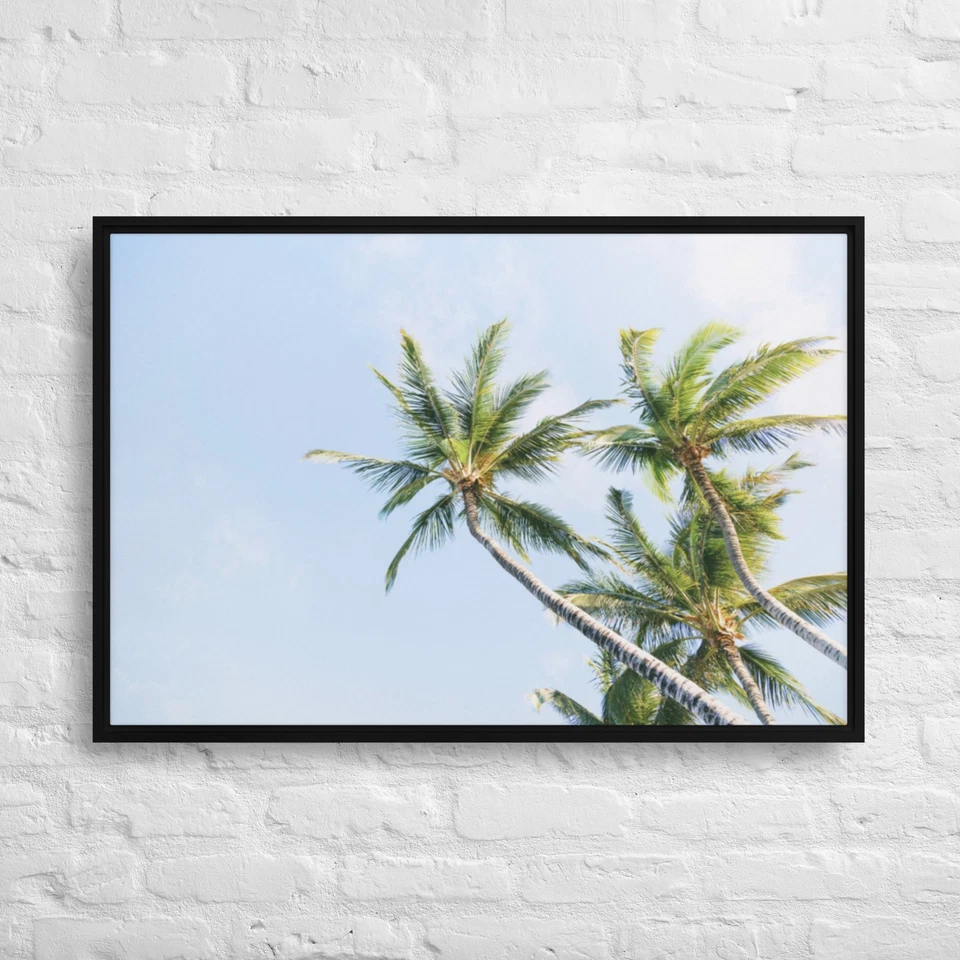 Bright green palm trees against a light blue sky. 36x24-Framed Canvas Print - Image 1 of 1